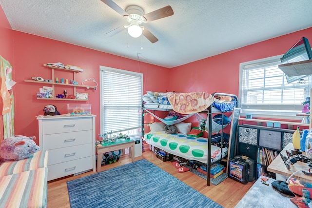 bedroom featuring ceiling fan, light hardwood / wood-style floors, and a textured ceiling