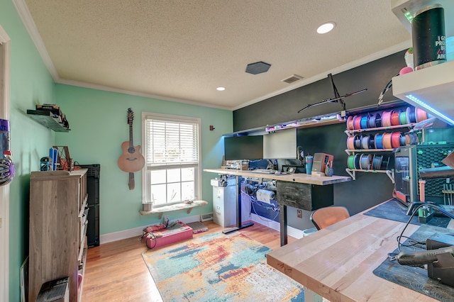 rec room with light hardwood / wood-style flooring, ornamental molding, and a textured ceiling