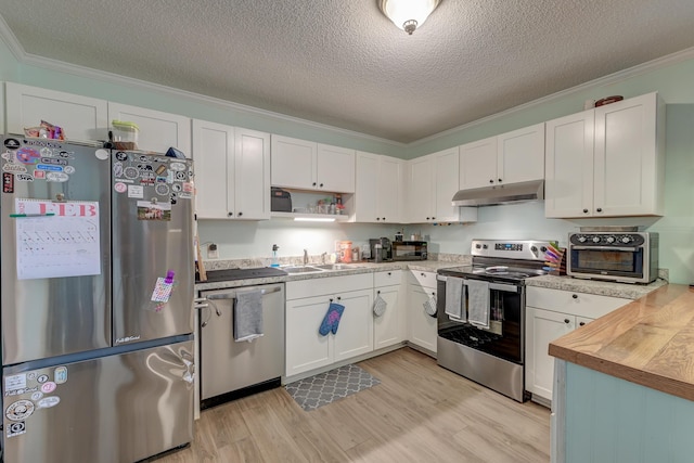 kitchen with sink, butcher block countertops, white cabinetry, ornamental molding, and appliances with stainless steel finishes