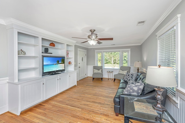 living room featuring ornamental molding, built in shelves, light wood-type flooring, and ceiling fan