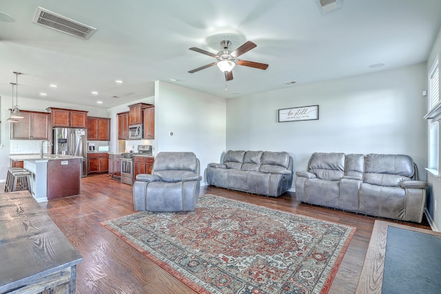 living room with visible vents, dark wood-style flooring, and ceiling fan