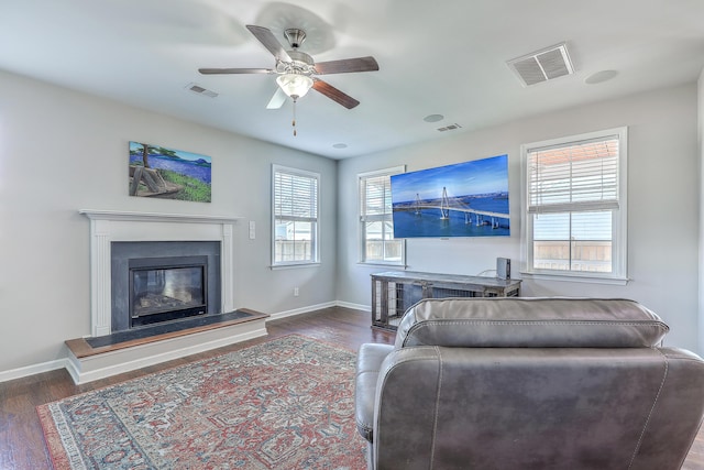 living area with visible vents, a ceiling fan, baseboards, and wood finished floors