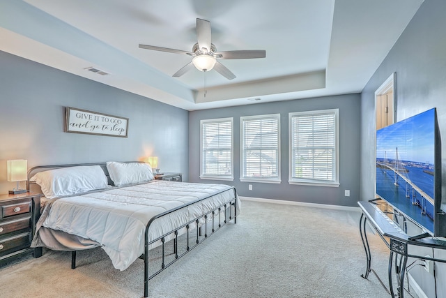 bedroom with carpet flooring, baseboards, visible vents, and a raised ceiling