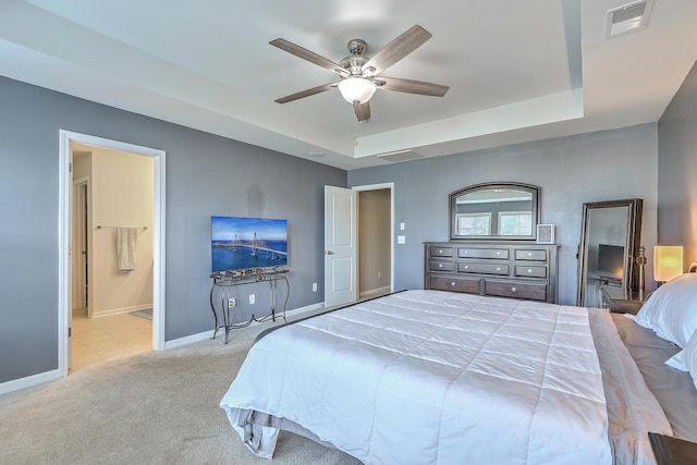 carpeted bedroom featuring a tray ceiling, visible vents, baseboards, and ensuite bathroom