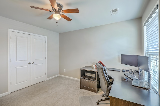 office space with visible vents, baseboards, ceiling fan, and light carpet