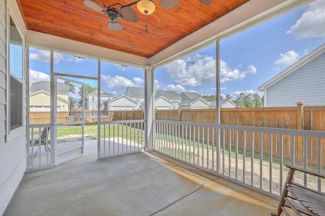 unfurnished sunroom with ceiling fan and a residential view