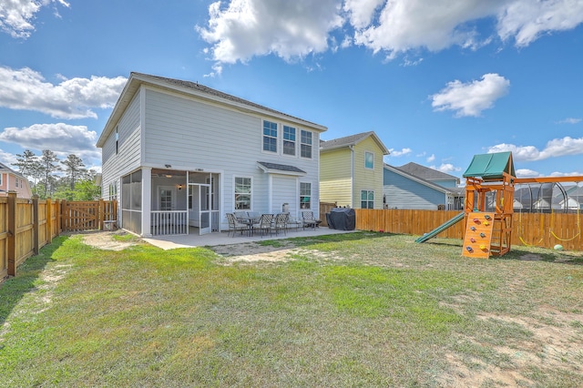 rear view of house with a lawn, a fenced backyard, a playground, and a sunroom