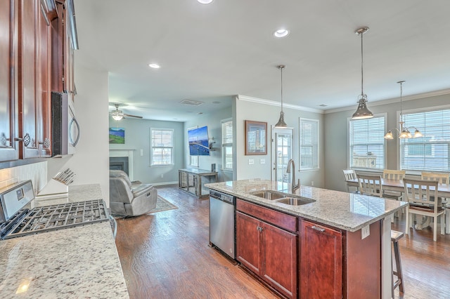 kitchen featuring ceiling fan with notable chandelier, a fireplace, open floor plan, a sink, and appliances with stainless steel finishes
