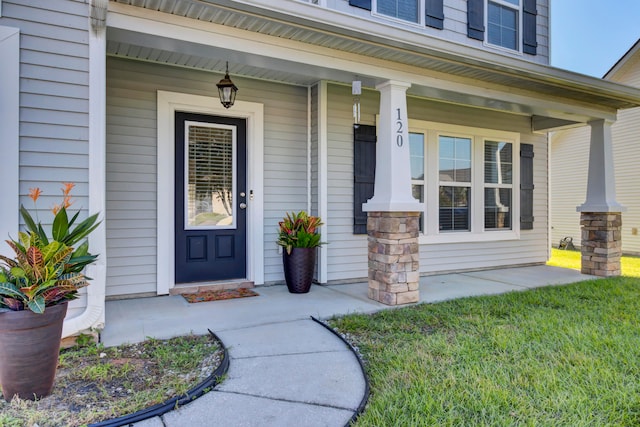 doorway to property with a porch and a yard