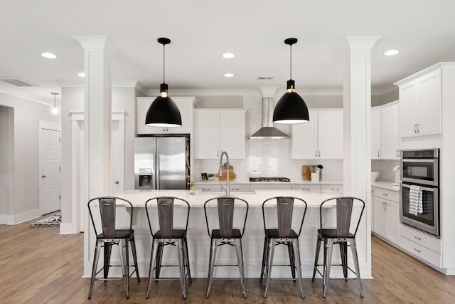 2828 Wagner Way, Mount Pleasant, SC 29466 - kitchen with stainless steel appliances, wall chimney exhaust hood, ornate columns, backsplash, and ornamental molding