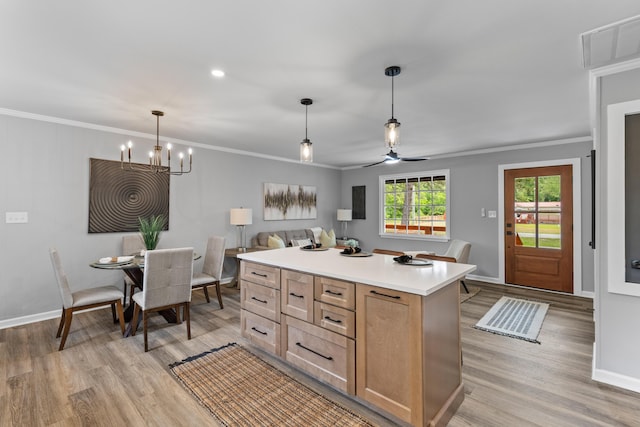 kitchen featuring light wood-type flooring, a chandelier, light countertops, baseboards, and ornamental molding