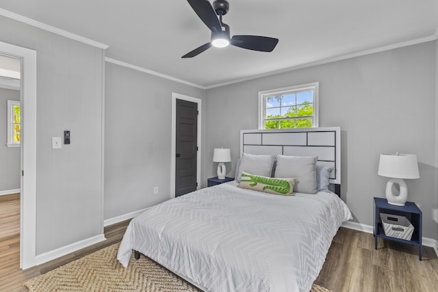 bedroom featuring wood finished floors, crown molding, baseboards, and a ceiling fan