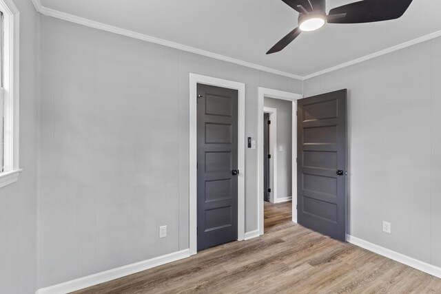 unfurnished bedroom with wood finished floors, crown molding, baseboards, and ceiling fan