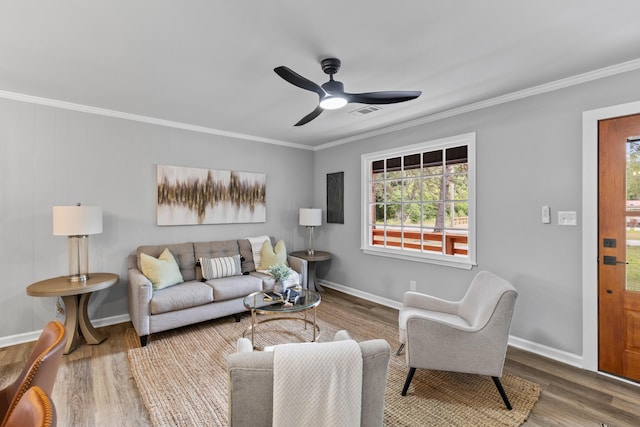 living room featuring plenty of natural light, ceiling fan, wood finished floors, crown molding, and baseboards
