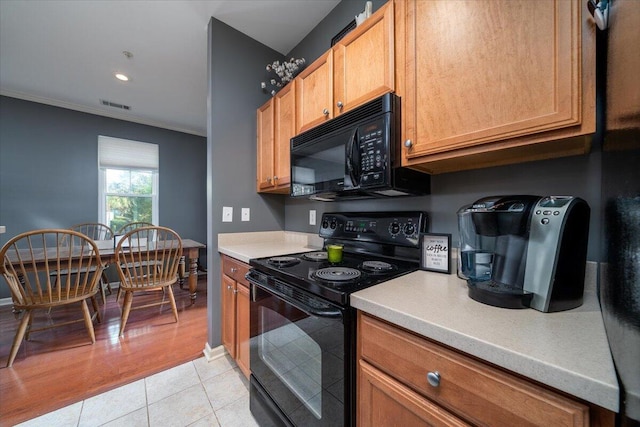 kitchen featuring light tile patterned flooring, ornamental molding, and black appliances