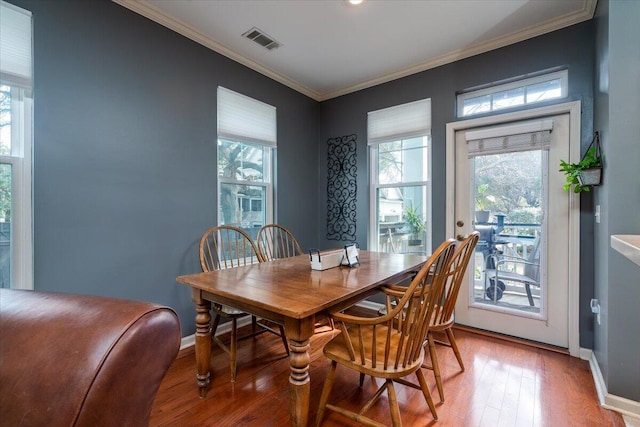 dining space with a healthy amount of sunlight, ornamental molding, and hardwood / wood-style floors