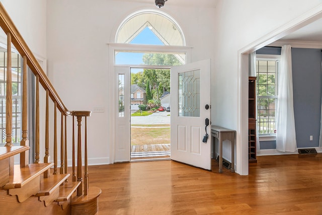 foyer with a healthy amount of sunlight, ornamental molding, and light hardwood / wood-style floors