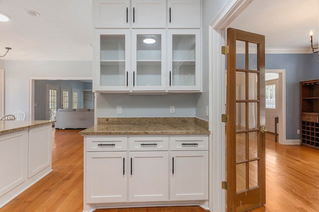 kitchen featuring crown molding, light wood-type flooring, and white cabinetry