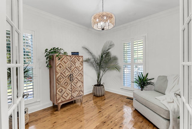 sitting room with a healthy amount of sunlight, light wood finished floors, and ornamental molding