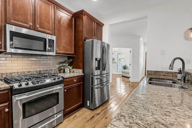 kitchen with decorative backsplash, appliances with stainless steel finishes, light stone countertops, crown molding, and a sink