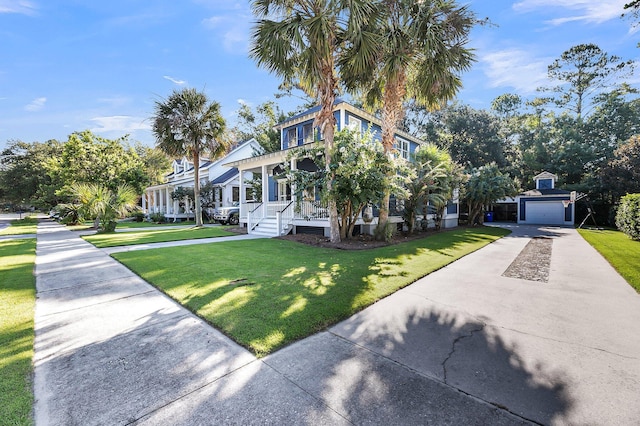 view of front facade featuring covered porch, an outbuilding, concrete driveway, and a front yard