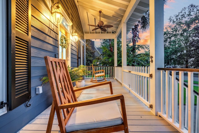 deck at dusk with covered porch and ceiling fan