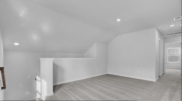 additional living space with light carpet and vaulted ceiling