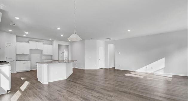 kitchen with sink, hanging light fixtures, hardwood / wood-style flooring, an island with sink, and white cabinetry