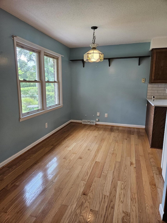 101 Brittany Ct, Summerville, SC 29485 - unfurnished dining area with light wood-type flooring, a textured ceiling, and baseboards