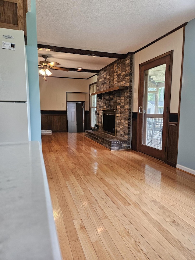 101 Brittany Ct, Summerville, SC 29485 - unfurnished living room with wainscoting, a textured ceiling, hardwood / wood-style flooring, a fireplace, and a ceiling fan