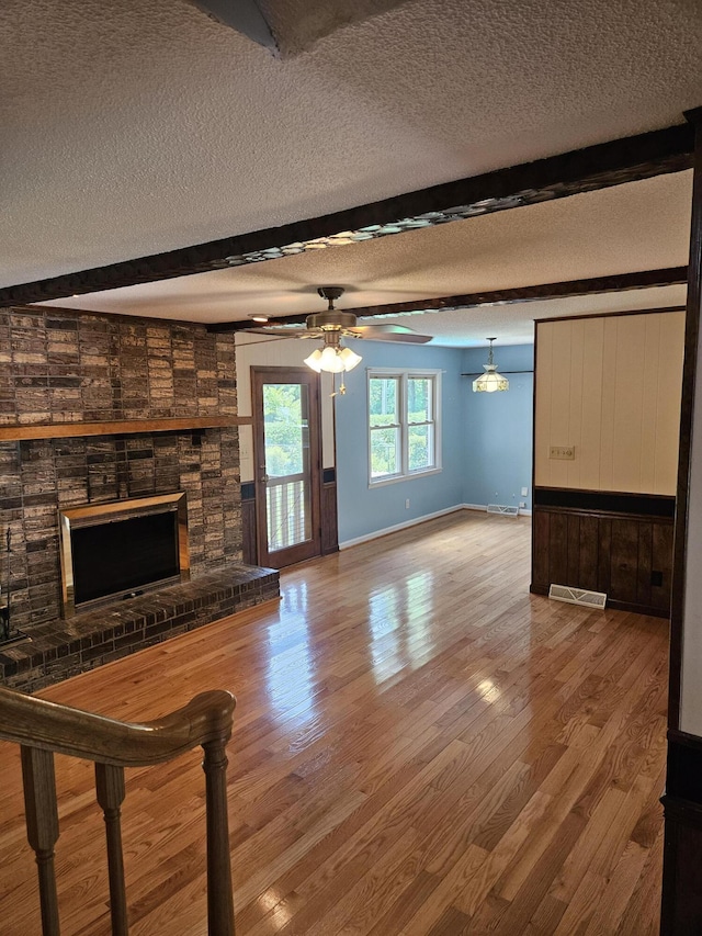 101 Brittany Ct, Summerville, SC 29485 - unfurnished living room featuring a fireplace, a textured ceiling, beam ceiling, wood finished floors, and ceiling fan