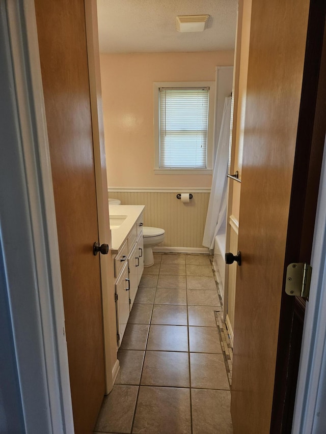 101 Brittany Ct, Summerville, SC 29485 - bathroom featuring a wainscoted wall, vanity, toilet, tile patterned floors, and a textured ceiling