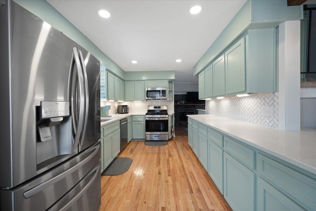 kitchen featuring stainless steel appliances, light wood-style flooring, decorative backsplash, and light countertops