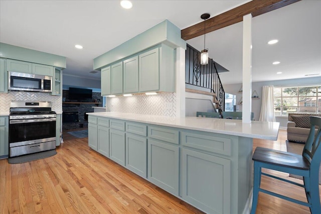 kitchen with light wood-type flooring, stainless steel appliances, light countertops, and decorative backsplash