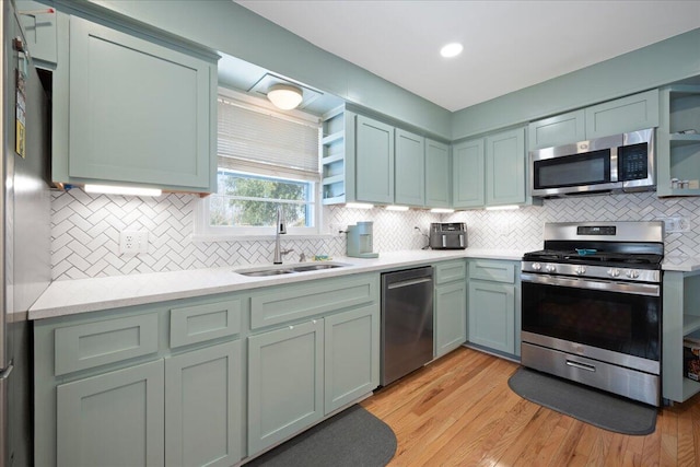 kitchen with a sink, backsplash, stainless steel appliances, light wood-style floors, and light countertops