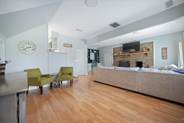 living room with a fireplace, crown molding, light wood-style floors, and visible vents