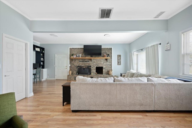 living room with visible vents, light wood-style flooring, and crown molding