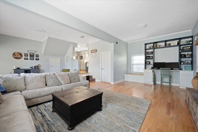 living room with visible vents, baseboards, light wood finished floors, and ornamental molding