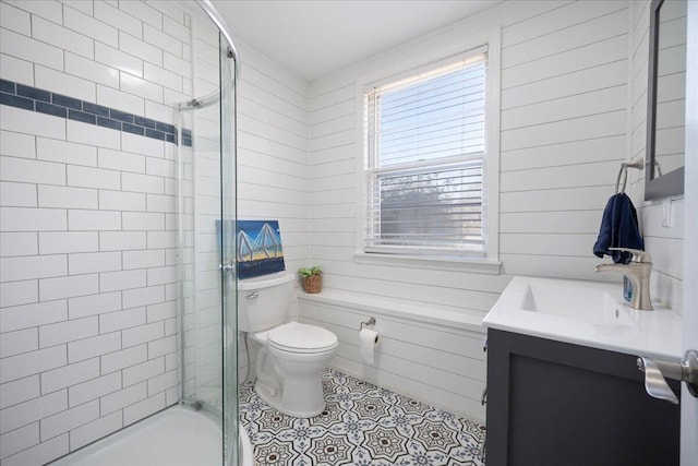 full bath with tile patterned flooring, wood walls, toilet, a tile shower, and vanity