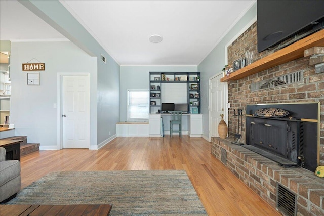 living room with wood finished floors, baseboards, visible vents, a fireplace, and ornamental molding