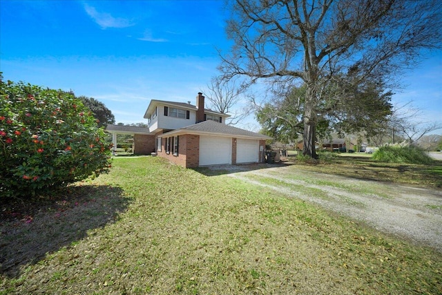 exterior space featuring brick siding, an attached garage, a lawn, a chimney, and driveway