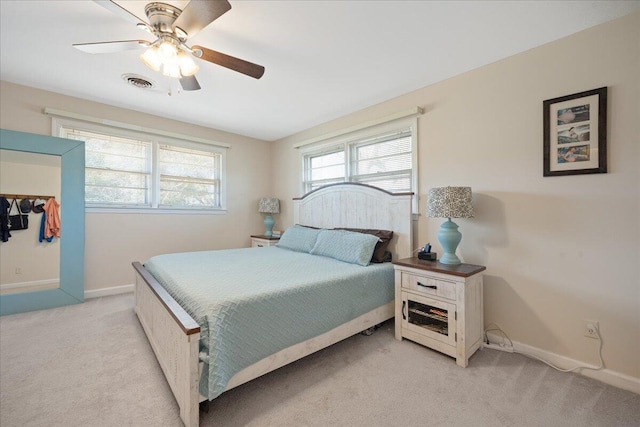 bedroom featuring visible vents, baseboards, light colored carpet, and a ceiling fan