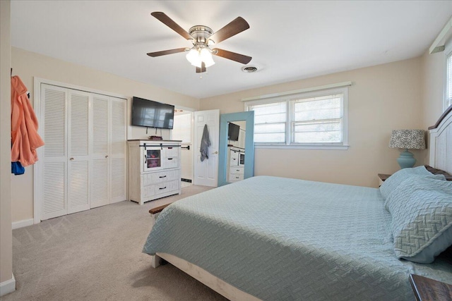 bedroom featuring visible vents, baseboards, ceiling fan, light colored carpet, and a closet