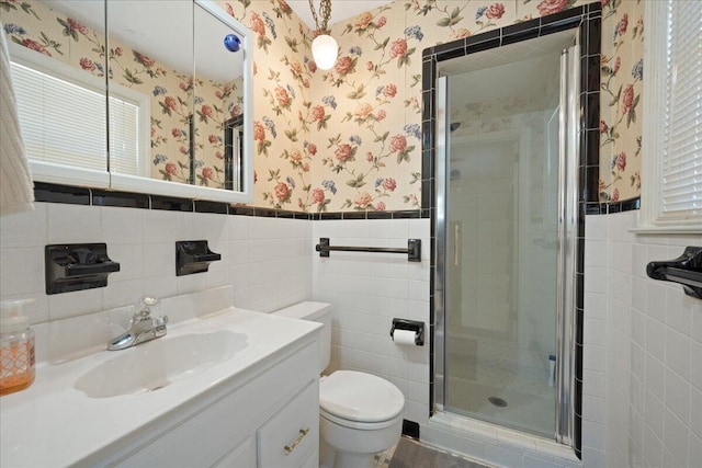 full bathroom with a wainscoted wall, toilet, a stall shower, wallpapered walls, and vanity