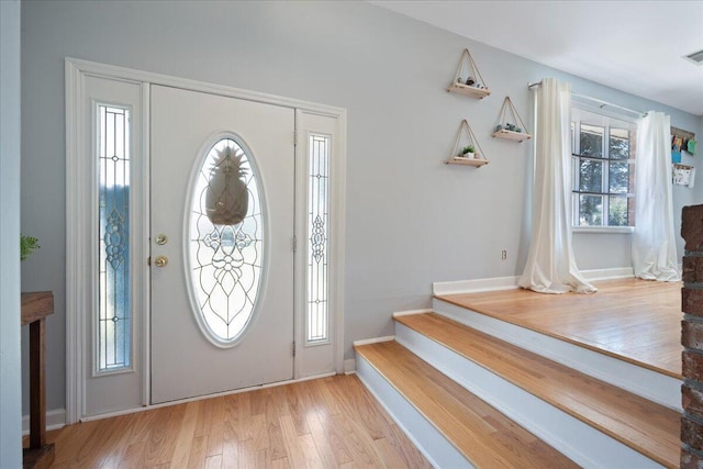 foyer entrance with visible vents, a healthy amount of sunlight, and wood finished floors