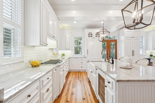 kitchen with white cabinets, an inviting chandelier, stainless steel gas cooktop, a large island, and light stone counters