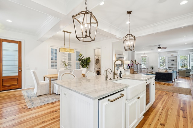 kitchen with white cabinetry, a center island with sink, decorative light fixtures, and sink