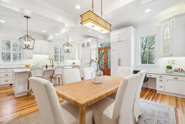 dining area with light hardwood / wood-style flooring, ornamental molding, beamed ceiling, and a healthy amount of sunlight