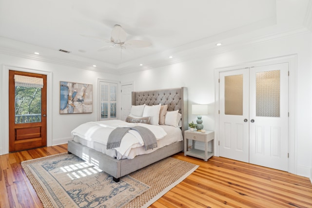 bedroom featuring ceiling fan, light hardwood / wood-style flooring, and a raised ceiling