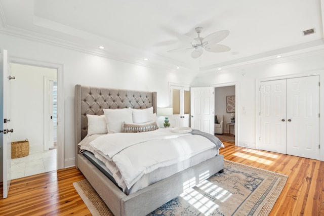 bedroom featuring a raised ceiling, ceiling fan, and hardwood / wood-style flooring